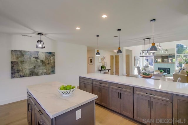 kitchen featuring pendant lighting, light stone counters, light hardwood / wood-style flooring, and a kitchen island