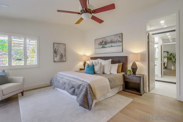 bedroom with ceiling fan, lofted ceiling, and light wood-type flooring