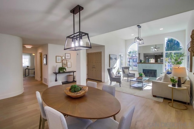 dining area with a tiled fireplace and light hardwood / wood-style floors