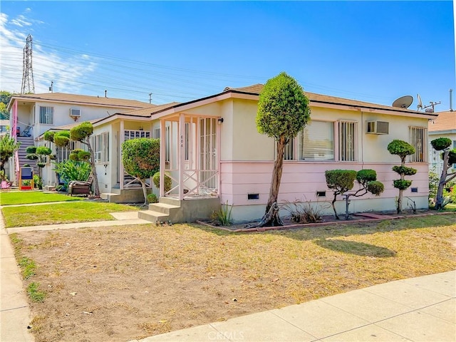 view of front of property with a wall unit AC and a front yard