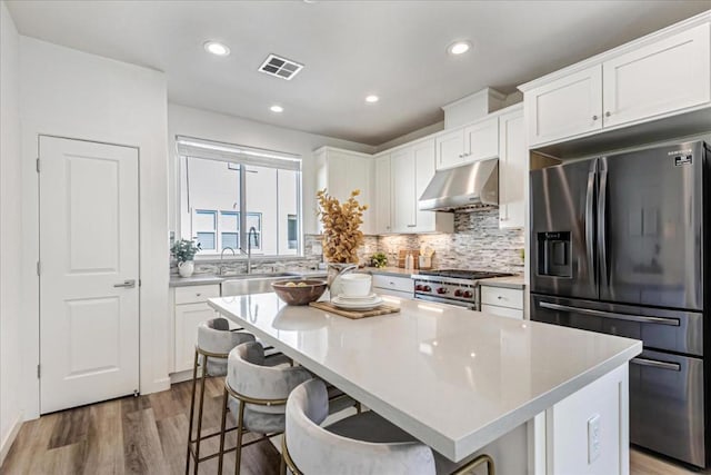 kitchen featuring white cabinetry, a kitchen bar, a kitchen island, and appliances with stainless steel finishes