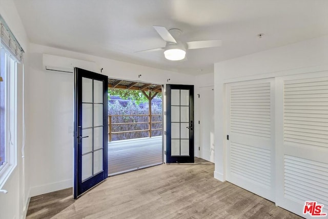 interior space with french doors, ceiling fan, a wall mounted air conditioner, and light hardwood / wood-style flooring