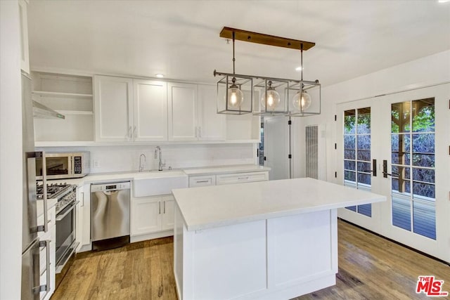 kitchen featuring sink, decorative light fixtures, a center island, appliances with stainless steel finishes, and white cabinets