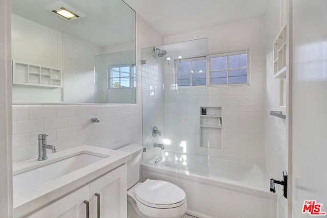 full bathroom featuring tile walls, backsplash, vanity, tiled shower / bath, and toilet