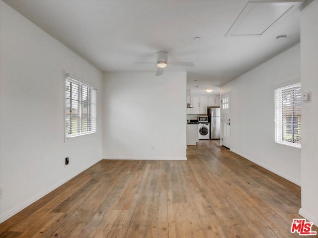 unfurnished living room featuring washer / dryer, light hardwood / wood-style floors, and ceiling fan