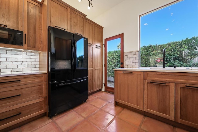 kitchen featuring sink, light tile patterned floors, backsplash, and black appliances