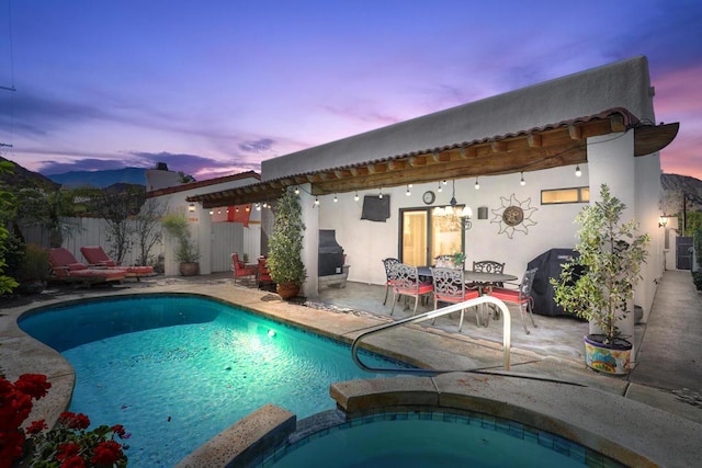 pool at dusk with a patio area