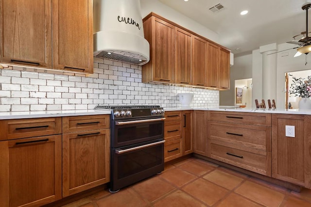 kitchen featuring ceiling fan, tasteful backsplash, island exhaust hood, tile patterned floors, and range with two ovens