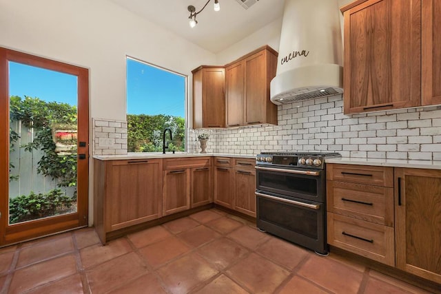 kitchen featuring tasteful backsplash, double oven range, custom exhaust hood, and sink