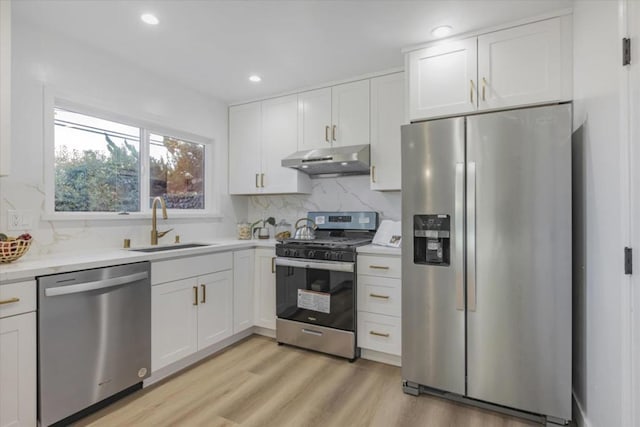 kitchen with stainless steel appliances, light stone countertops, white cabinets, and light hardwood / wood-style floors