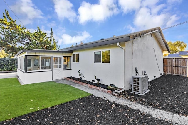 rear view of property featuring a yard, ac unit, and a sunroom