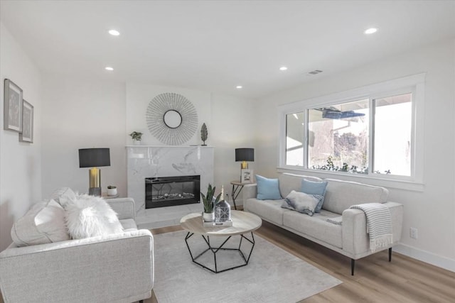 living room featuring a high end fireplace and light wood-type flooring