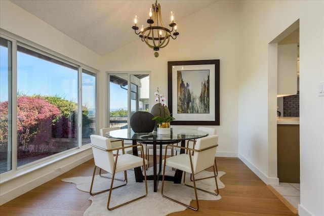 dining area with a notable chandelier, lofted ceiling, and light wood-type flooring