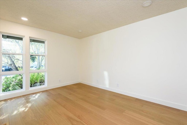 spare room featuring a textured ceiling and light hardwood / wood-style floors