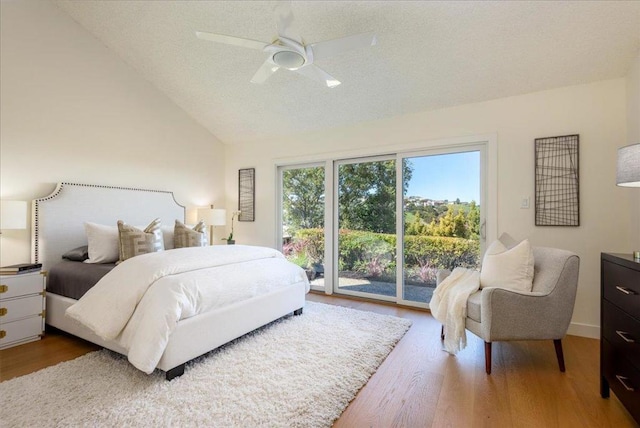 bedroom featuring hardwood / wood-style floors, lofted ceiling, access to outside, ceiling fan, and a textured ceiling