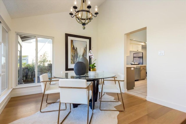 dining space featuring a notable chandelier, vaulted ceiling, and light hardwood / wood-style floors