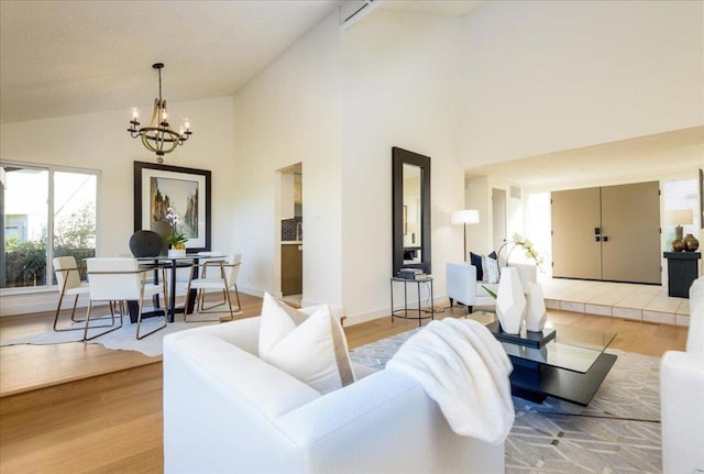 living room with a chandelier, high vaulted ceiling, and light hardwood / wood-style flooring