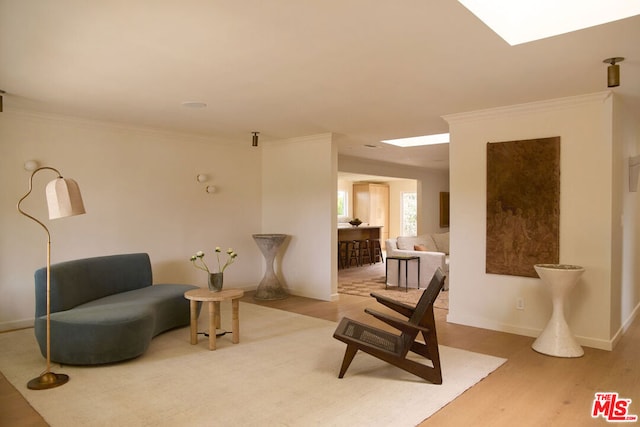 sitting room with ornamental molding and light wood-type flooring