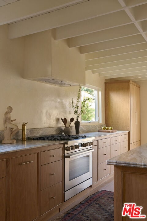 kitchen featuring beamed ceiling, stainless steel range with gas stovetop, and light brown cabinets