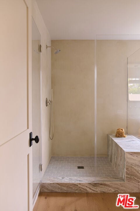 bathroom featuring hardwood / wood-style floors and a tile shower