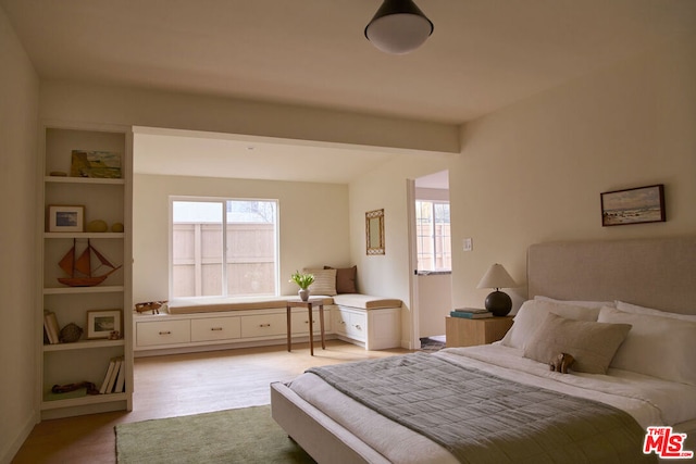 bedroom with beamed ceiling and light wood-type flooring