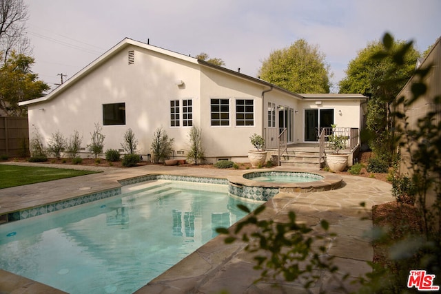 rear view of property with a pool with hot tub and a patio