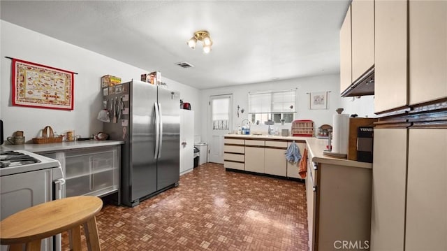 kitchen with white cabinetry, sink, stainless steel fridge, and white stove