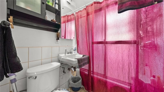 bathroom featuring toilet, sink, and tile walls