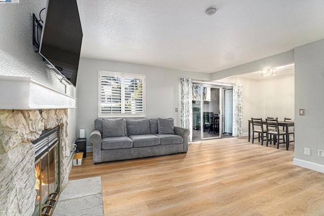 living room featuring a fireplace, light hardwood / wood-style flooring, and a textured ceiling