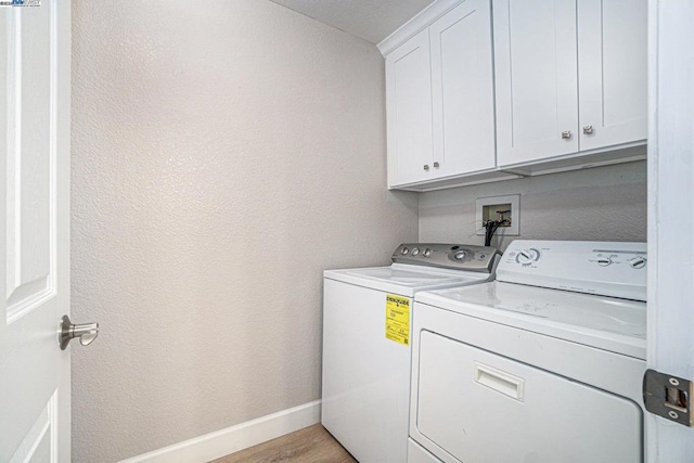 washroom featuring cabinets, independent washer and dryer, and light hardwood / wood-style floors