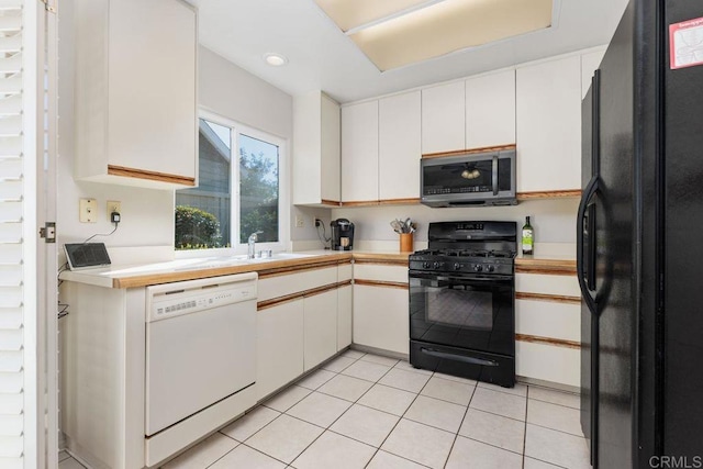 kitchen featuring light tile patterned flooring, white cabinets, sink, and black appliances