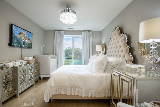 bedroom with an inviting chandelier and light hardwood / wood-style flooring