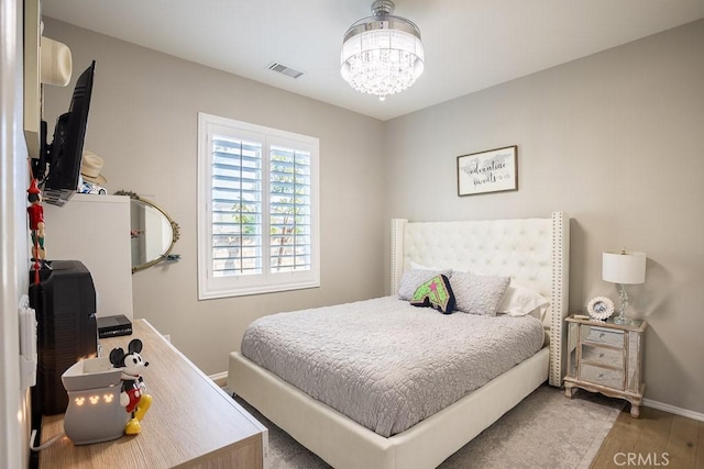 bedroom featuring a notable chandelier and hardwood / wood-style flooring