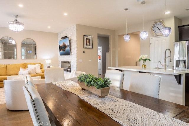 dining area featuring a fireplace, sink, and light wood-type flooring