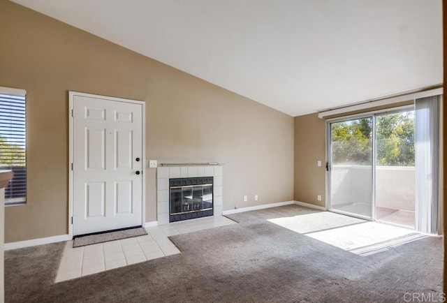 unfurnished living room featuring lofted ceiling, a tiled fireplace, and light colored carpet