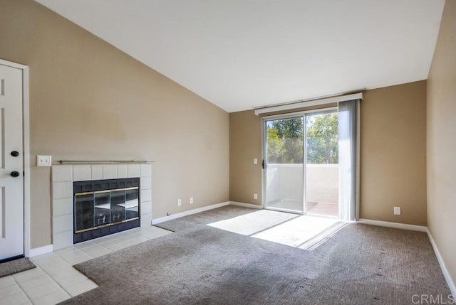 unfurnished living room with a tiled fireplace, vaulted ceiling, and light carpet