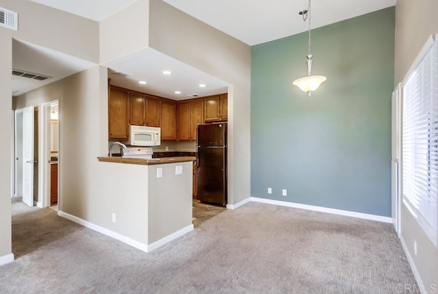 kitchen with sink, black fridge, hanging light fixtures, kitchen peninsula, and light colored carpet