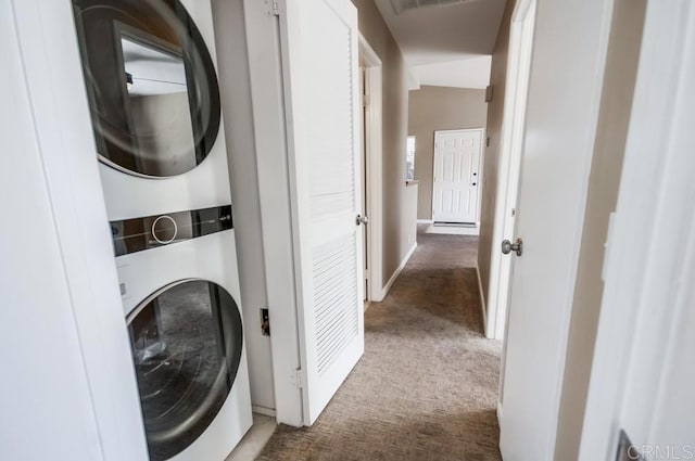 washroom featuring stacked washer / drying machine and dark carpet