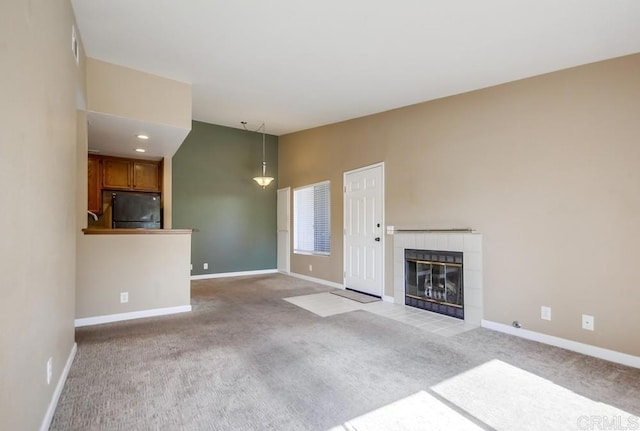 unfurnished living room featuring a tiled fireplace, carpet floors, and vaulted ceiling