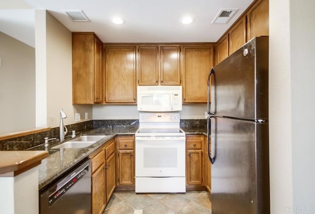 kitchen featuring light tile patterned flooring, sink, dark stone countertops, and white appliances