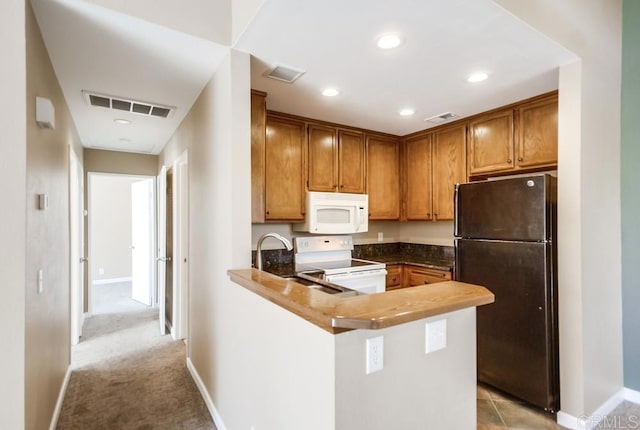 kitchen with sink, white appliances, light colored carpet, and kitchen peninsula