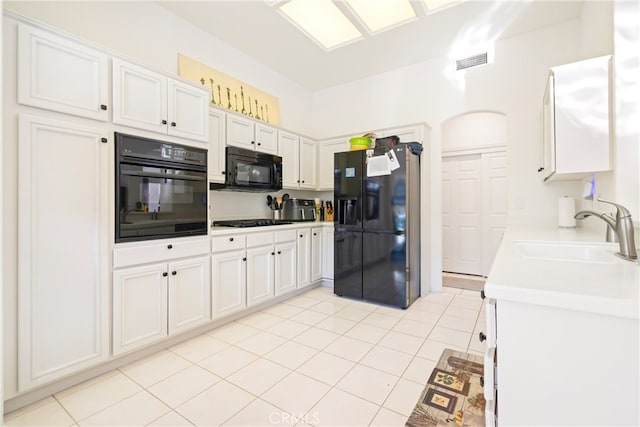 kitchen with light tile patterned flooring, sink, white cabinets, and black appliances