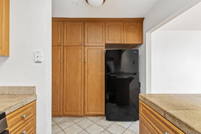 kitchen featuring black refrigerator and light tile patterned floors