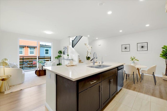 kitchen with stainless steel dishwasher, sink, light hardwood / wood-style flooring, and a center island with sink