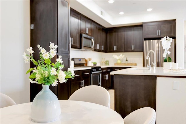 kitchen featuring dark brown cabinetry, stainless steel appliances, sink, and an island with sink