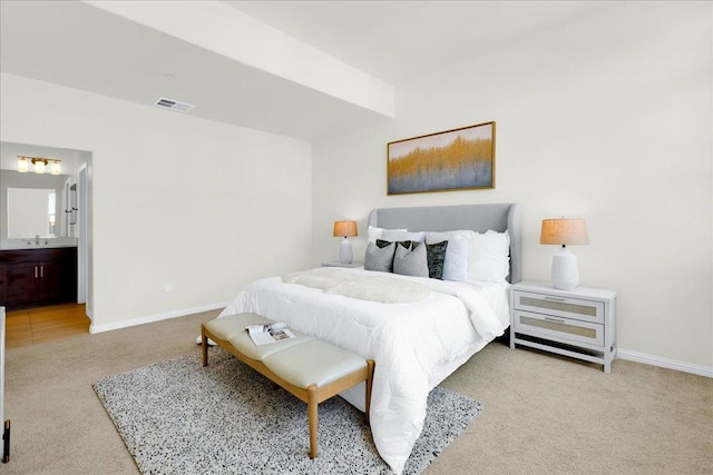 bedroom with ensuite bath and light colored carpet