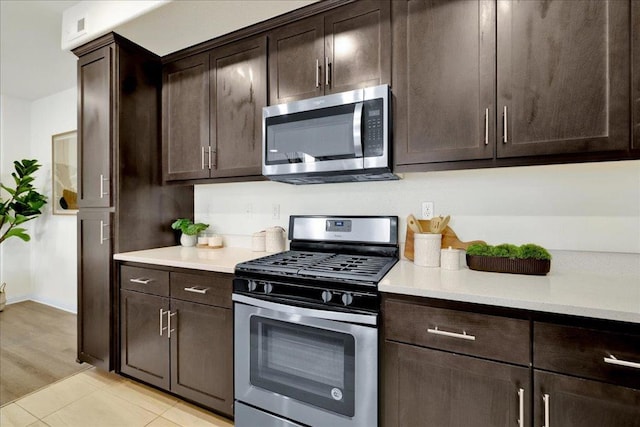 kitchen with appliances with stainless steel finishes, light tile patterned floors, and dark brown cabinetry