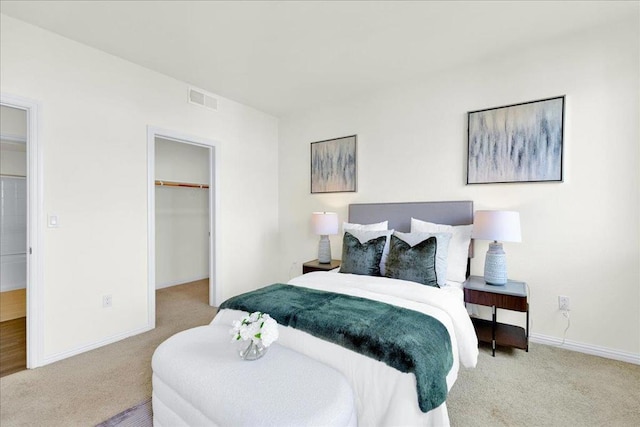 carpeted bedroom featuring a walk in closet and a closet