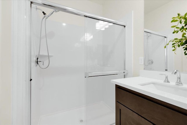 bathroom featuring a shower with door and vanity