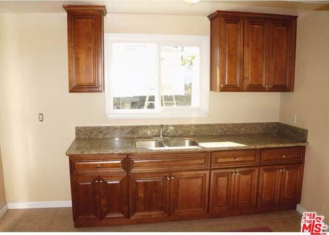 kitchen featuring tile patterned flooring, stone countertops, and sink